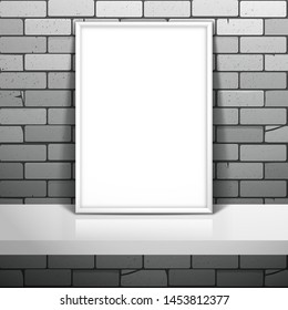 White empty frame for a picture or a poster stands near the brick wall on the shelf. Mockup for design with shadow