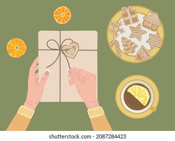 White female hands open gift box wrapped into kraft paper and twine ribbon. Top view dry orange, cinnamon, cup of tea, gingerbread cookies. Eco Christmas concept. Hand drawn vector illustration