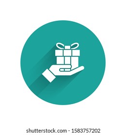 White Gift box in hand icon isolated with long shadow. Merry Christmas and Happy New Year. Green circle button. Vector Illustration
