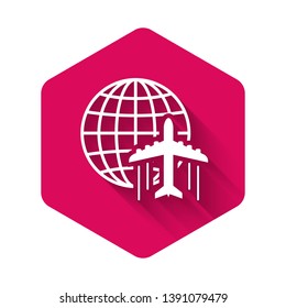 White Globe with flying plane icon isolated with long shadow. Airplane fly around the planet earth. Aircraft world icon. Pink hexagon button. Vector Illustration