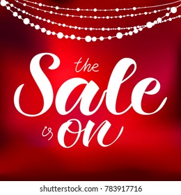 White hand drawn "The sale is on" typography lettering poster for ad, offer, coupon, shopping, websites. Vector illustration EPS 10 on red background with white beads for booklet, brochure, poster