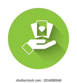 White Hand holding playing cards icon isolated with long shadow. Casino game design. Green circle button. Vector