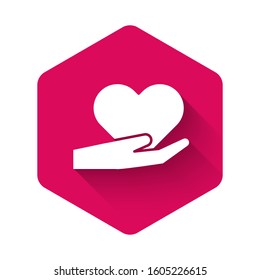 White Heart on hand icon isolated with long shadow. Hand giving love symbol. Valentines day symbol. Pink hexagon button. Vector Illustration