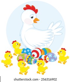 White hen sitting on painted Easter eggs surrounded by little yellow chicks