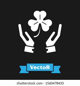White Human hands holding four leaf clover icon isolated on black background. Happy Saint Patrick day.  Vector Illustration