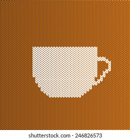White knitted cup of coffee or tea on a brown background