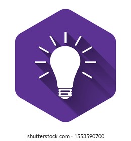 White Light bulb with rays shine icon isolated with long shadow. Energy and idea symbol. Lamp electric. Purple hexagon button. Vector Illustration