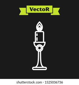 White line Burning candle in candlestick icon isolated on black background. Old fashioned lit candle. Cylindrical candle stick with burning flame.  Vector Illustration