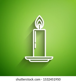 White line Burning candle in candlestick icon isolated on green background. Old fashioned lit candle. Cylindrical candle stick with burning flame.  Vector Illustration