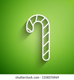 White line Christmas candy cane with stripes icon isolated on green background. Merry Christmas and Happy New Year.  Vector Illustration