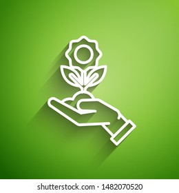 White line Hand holding flower icon isolated on green background. Seed and seedling. Planting sapling. Ecology concept.  Vector Illustration
