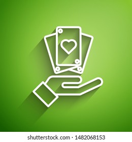 White line Hand holding playing cards icon isolated on green background. Casino game design.  Vector Illustration