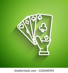 White line Hand holding playing cards icon isolated on green background. Casino game design.  Vector Illustration