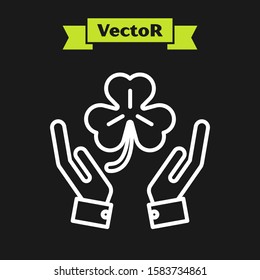 White line Human hands holding four leaf clover icon isolated on black background. Happy Saint Patrick day.  Vector Illustration