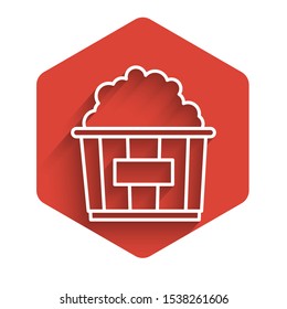 White line Popcorn in cardboard box icon isolated with long shadow. Popcorn bucket box. Red hexagon button. Vector Illustration