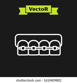 White line Teeth with braces icon isolated on black background. Alignment of bite of teeth, dental row with with braces. Dental concept.  Vector Illustration