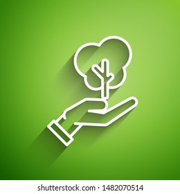 White line Tree in hand of environmental protection icon isolated on green background. Seed and seedling. Planting sapling. Ecology concept.  Vector Illustration