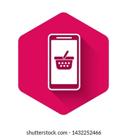 White Mobile phone and shopping basket icon isolated with long shadow. Online buying symbol. Supermarket basket symbol. Pink hexagon button. Vector Illustration