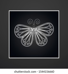 White openwork butterfly on a dark background in a frame