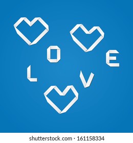 White origami paper heart and love word on blue background.