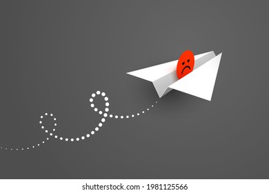White paper airplane and red unhappy face icon over dark background. Concept of bad news, bad mood, expression of dissatisfaction, negative feedback and user experience