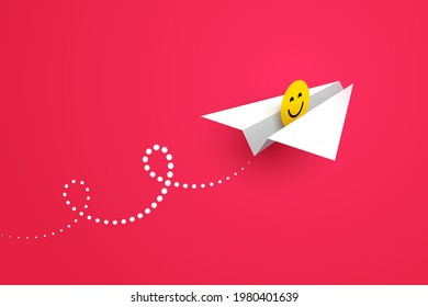 White paper airplane and yellow happy smiling face icon over red background. Concept of good news, sending greetings, wishing good mood, positive feedback and user experience