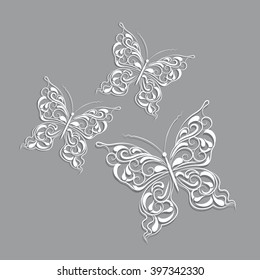White paper butterflies with vintage pattern on gray background.