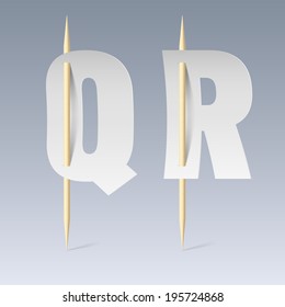 White paper cut font on toothpicks on grey background. Q and R letters