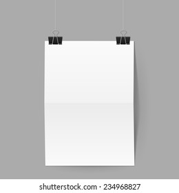 White paper folded in half hands on black clips on grey background