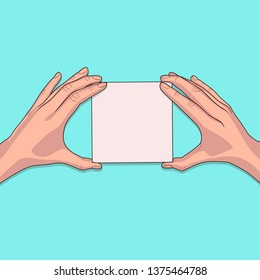 White piece of paper in the female hands on blue background. Blank sheet of paper