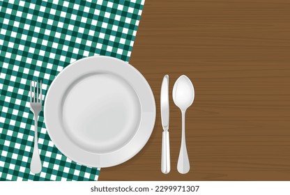 white plate, fork, spoon, and knife on a wooden table with a green checked tablecloth and copy space.