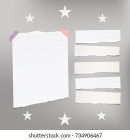 White ripped lined note, notebook paper for message or text stuck with sticky tape on gray background with stars.