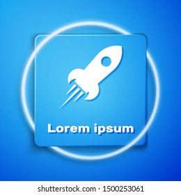 White Rocket ship with fire icon isolated on blue background. Space travel. Blue square button. Vector Illustration