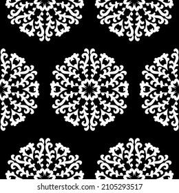 White round lace patterns on a black background. Beautiful seamless background with floral mandalas. Black and white. Vector vintage round ornament.