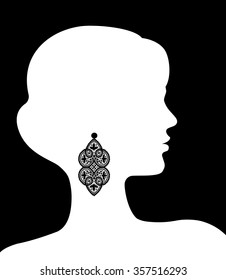 White silhouette of a female head with a lace earring on black background