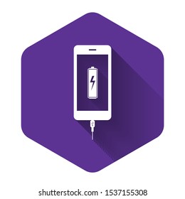 White Smartphone battery charge icon isolated with long shadow. Phone with a low battery charge and with USB connection. Purple hexagon button. Vector Illustration