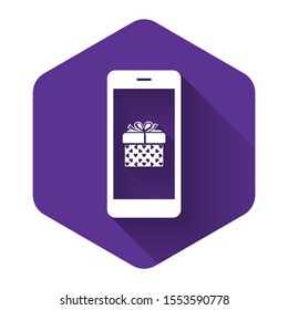 White Smartphone with gift box and heart symbol on the screen icon isolated with long shadow. Valentine's day symbol. The online store, e-shopping. Purple hexagon button. Vector Illustration
