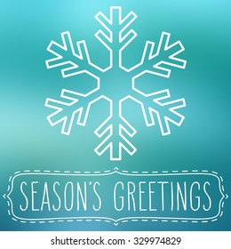 White snowflake over blue square abstract smooth blur background with hand written season's greetings in a frame.