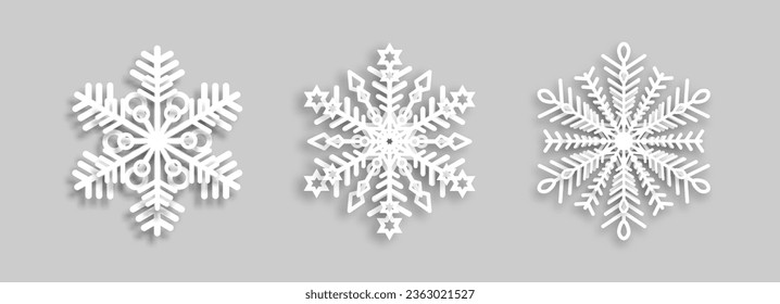 Copos de nieve blancos con efecto de papel sobre un fondo gris para el diseño invernal. Un conjunto de copos de nieve. Un símbolo de Navidad y Año Nuevo. EPS vectorial 10.