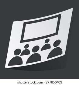 White sticker with black image of audience in front of screen, on black background