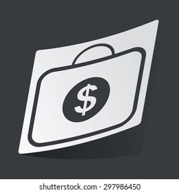 White sticker with black image of bag with dollar symbol, on black background
