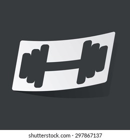 White sticker with black image of barbell, on black background