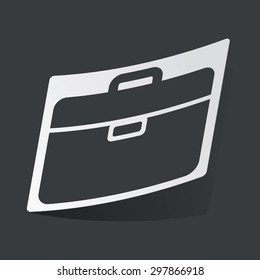 White sticker with black image of briefcase, on black background