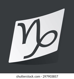 White sticker with black image of Capricorn zodiac symbol, on black background