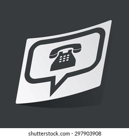White sticker with black image of chat bubble with old phone, on black background