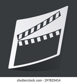 White sticker with black image of clapperboard, on black background