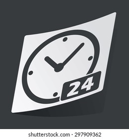 White sticker with black image of clock with text 24, on black background