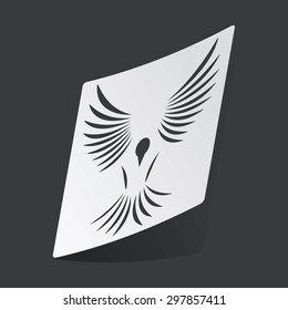 White sticker with black image of flying bird, on black background