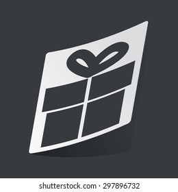 White sticker with black image of gift box, on black background