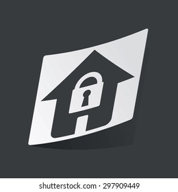 White sticker with black image of house with padlock, on black background
